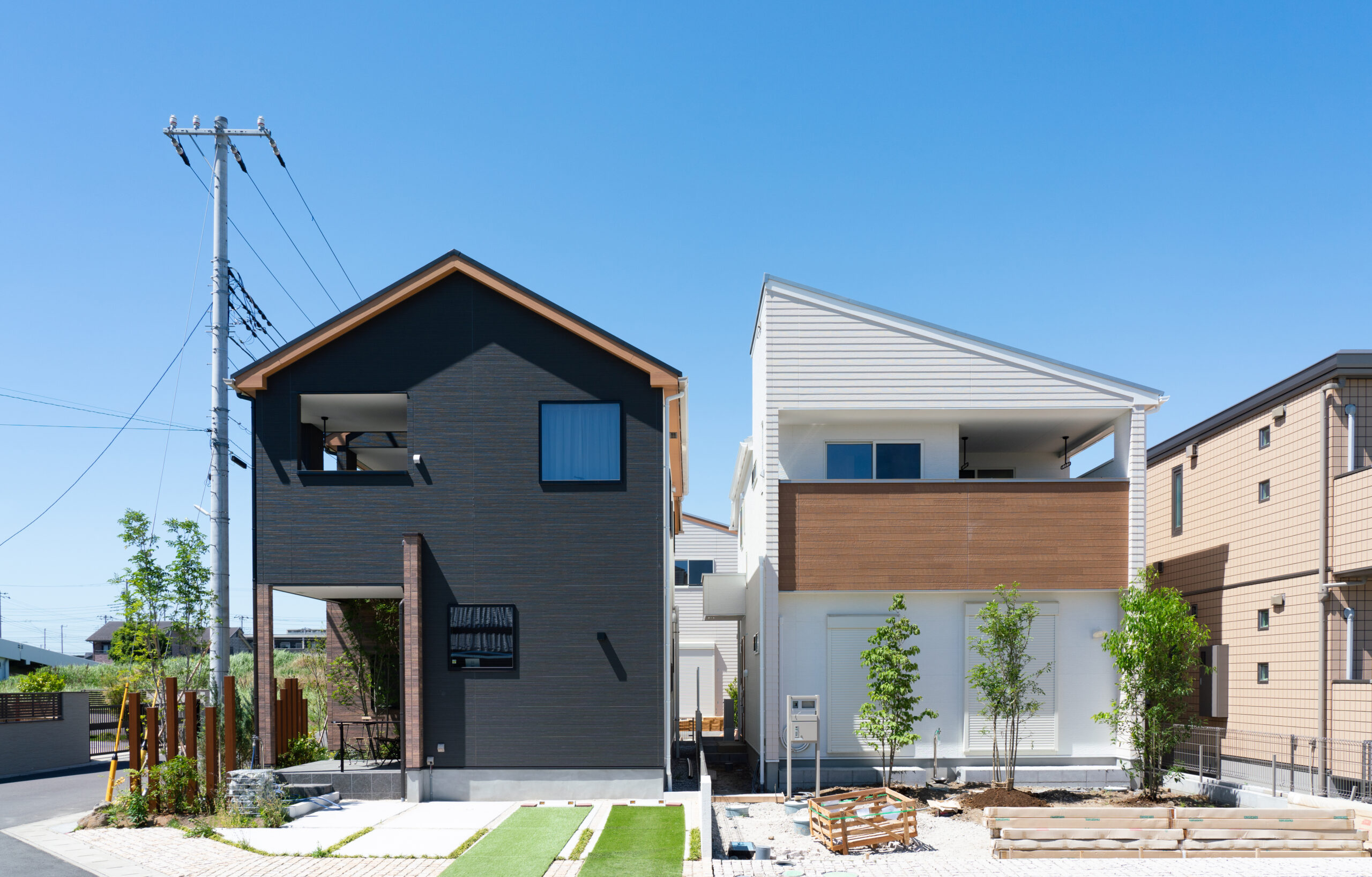 住宅街に並んで建つ、黒い切妻屋根と白い外壁の家